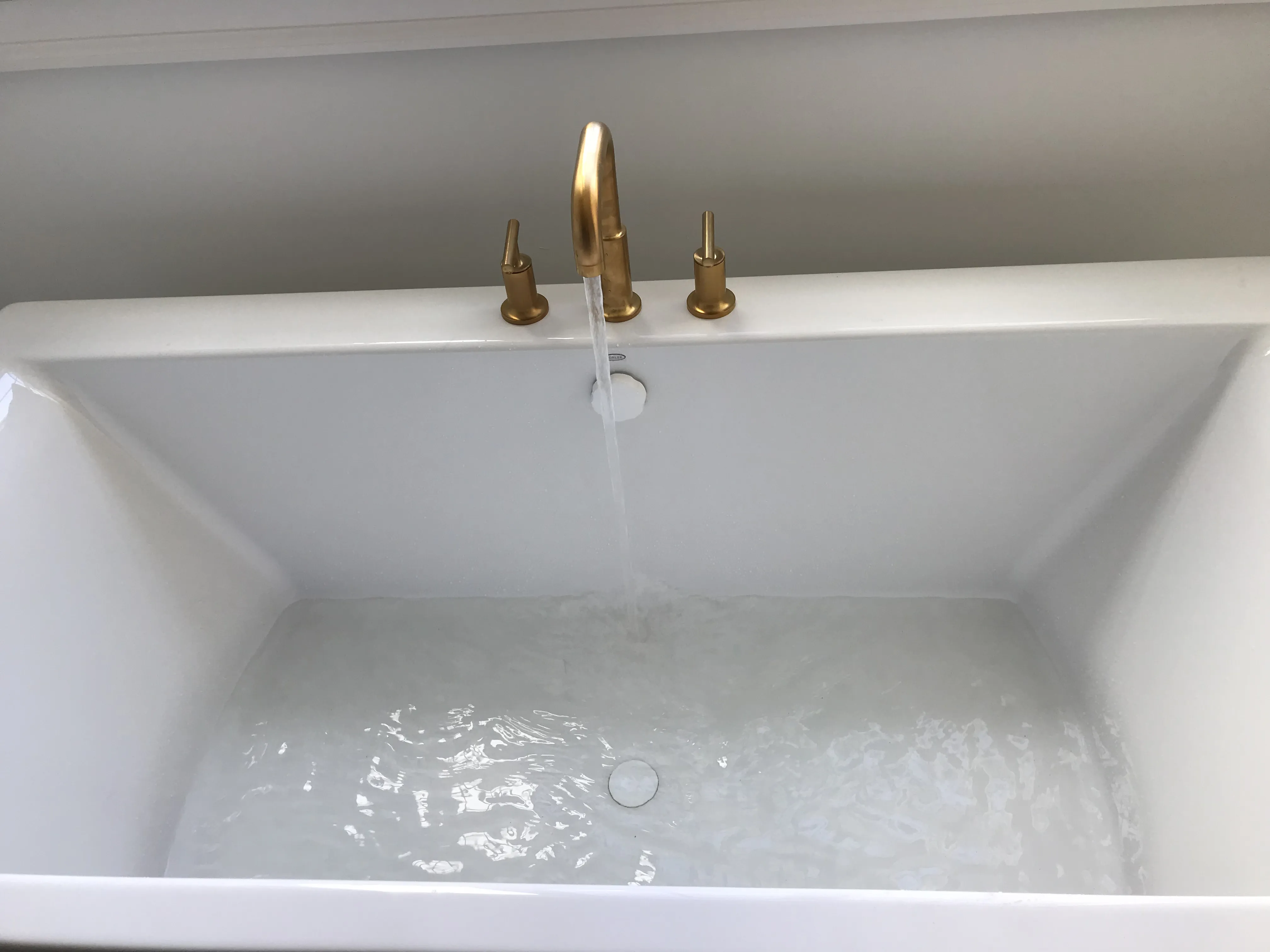 Gold faucet filling white freestanding bathtub