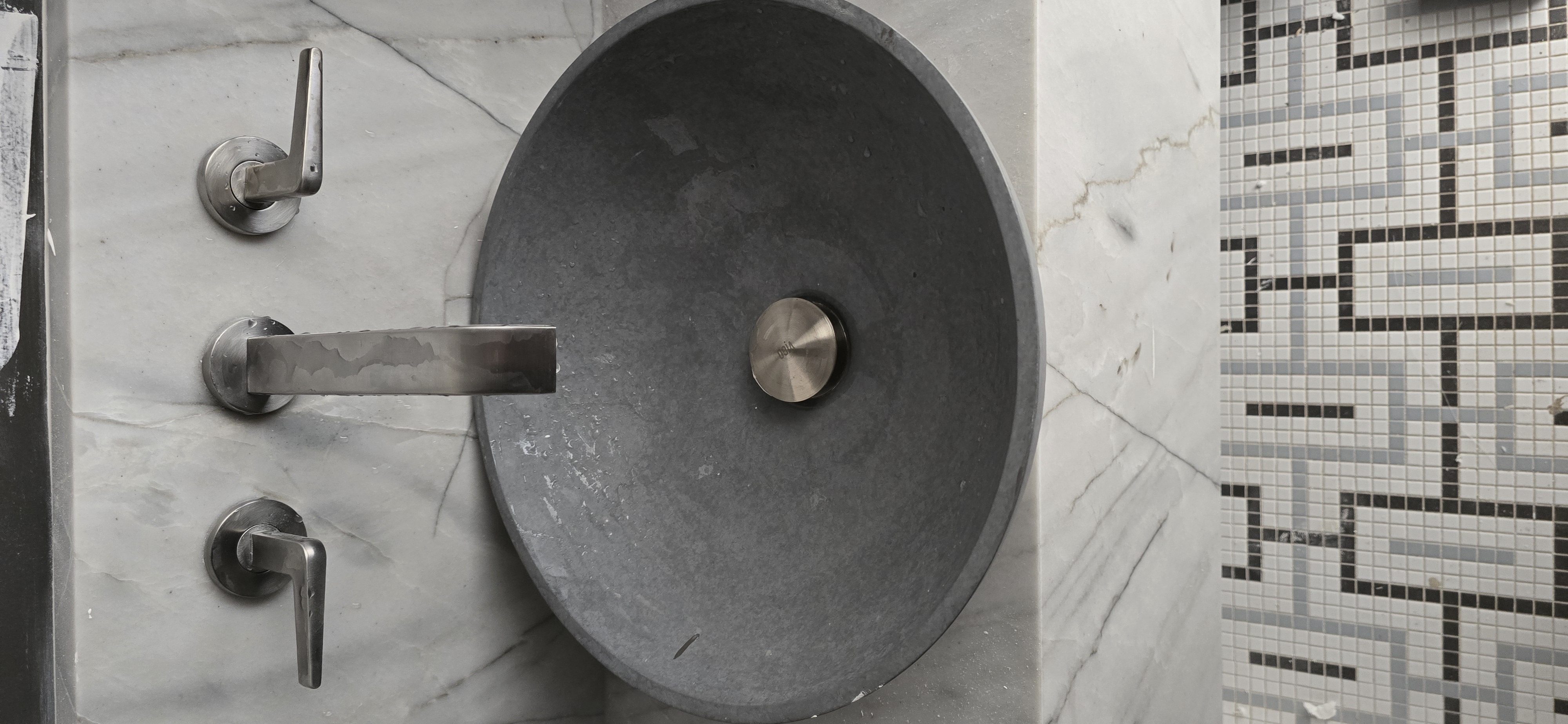 Stone vessel sink with wall-mounted faucet and marble tile