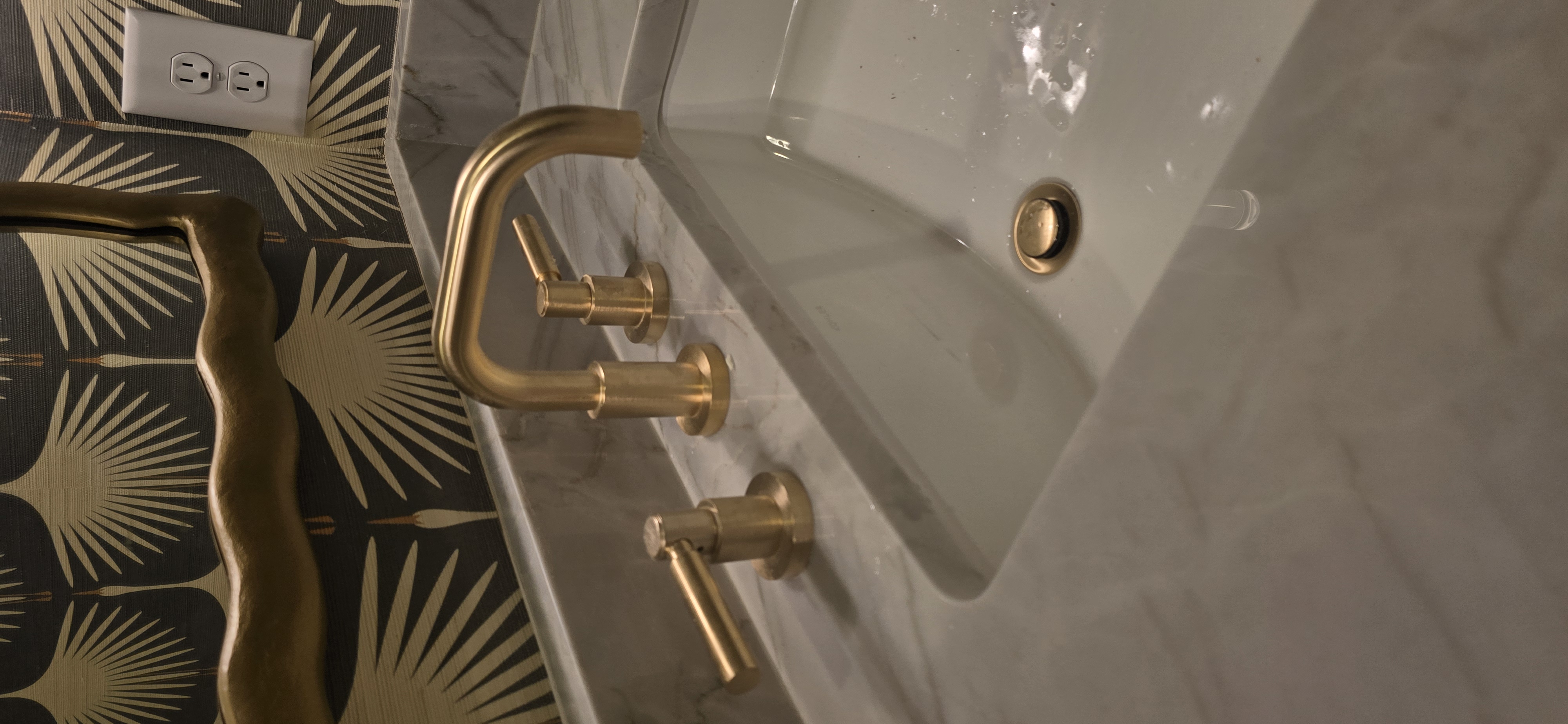 Gold widespread faucet on marble vanity