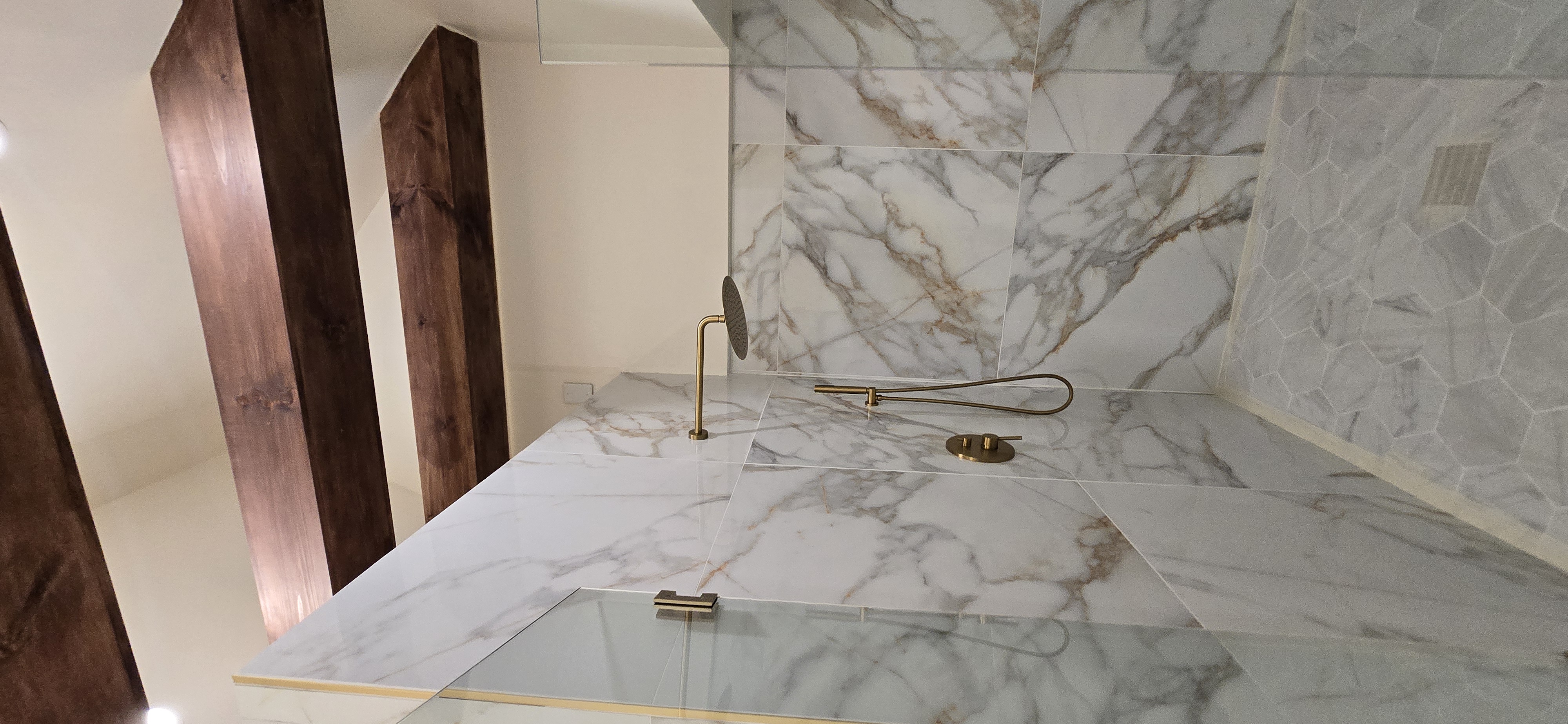 Luxury marble shower with gold rain shower and wood beam ceiling