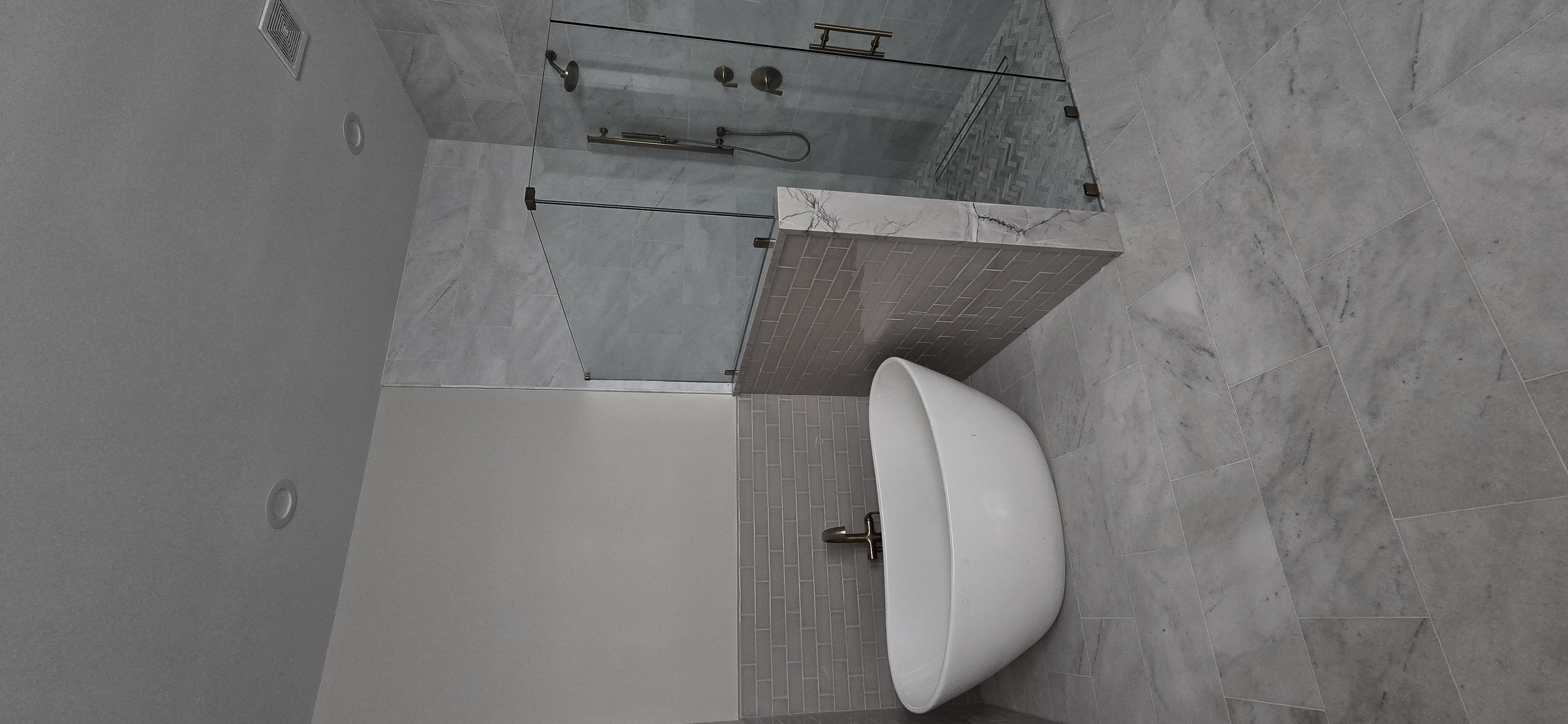 Freestanding tub with marble tile and glass shower enclosure