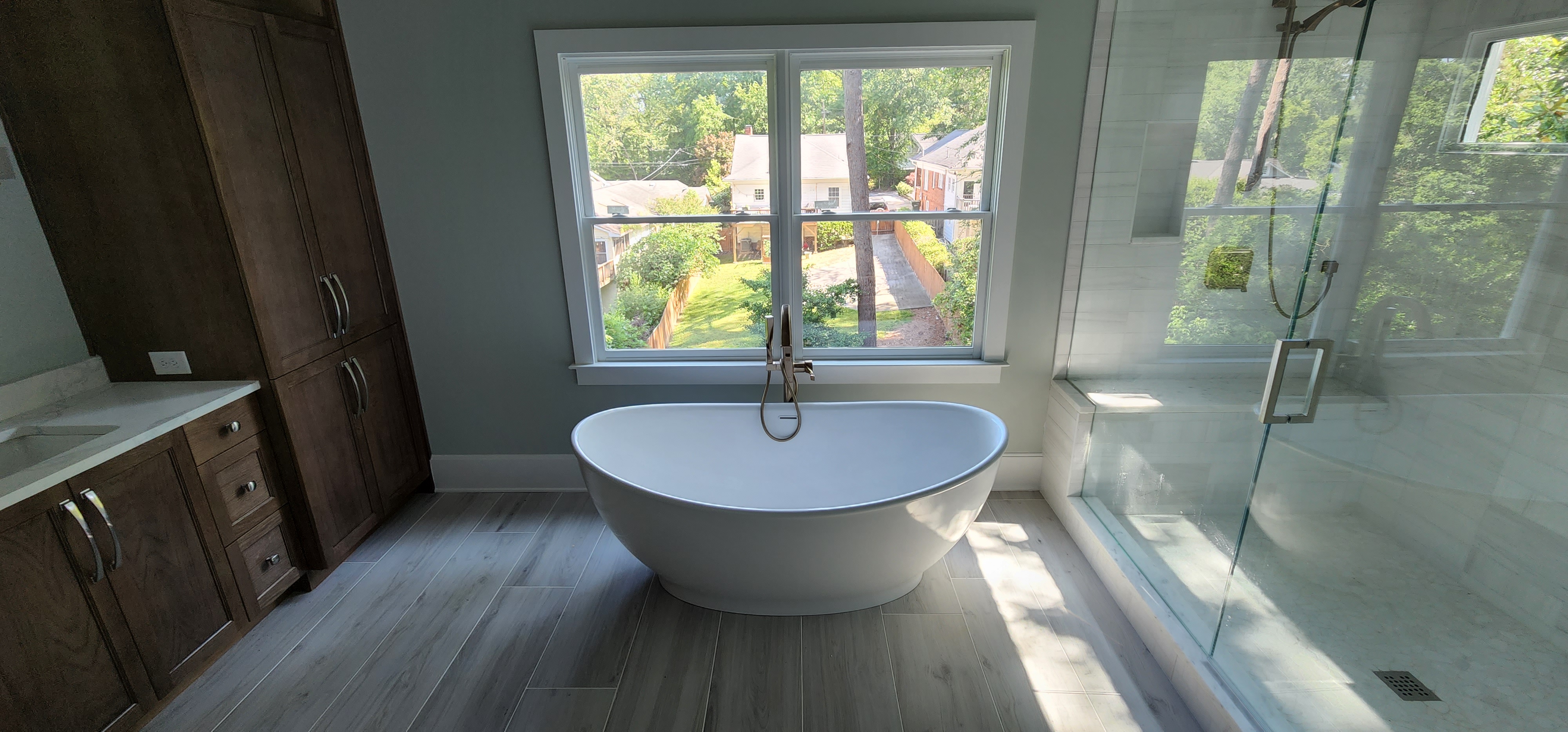 Freestanding tub with wood cabinetry and glass shower