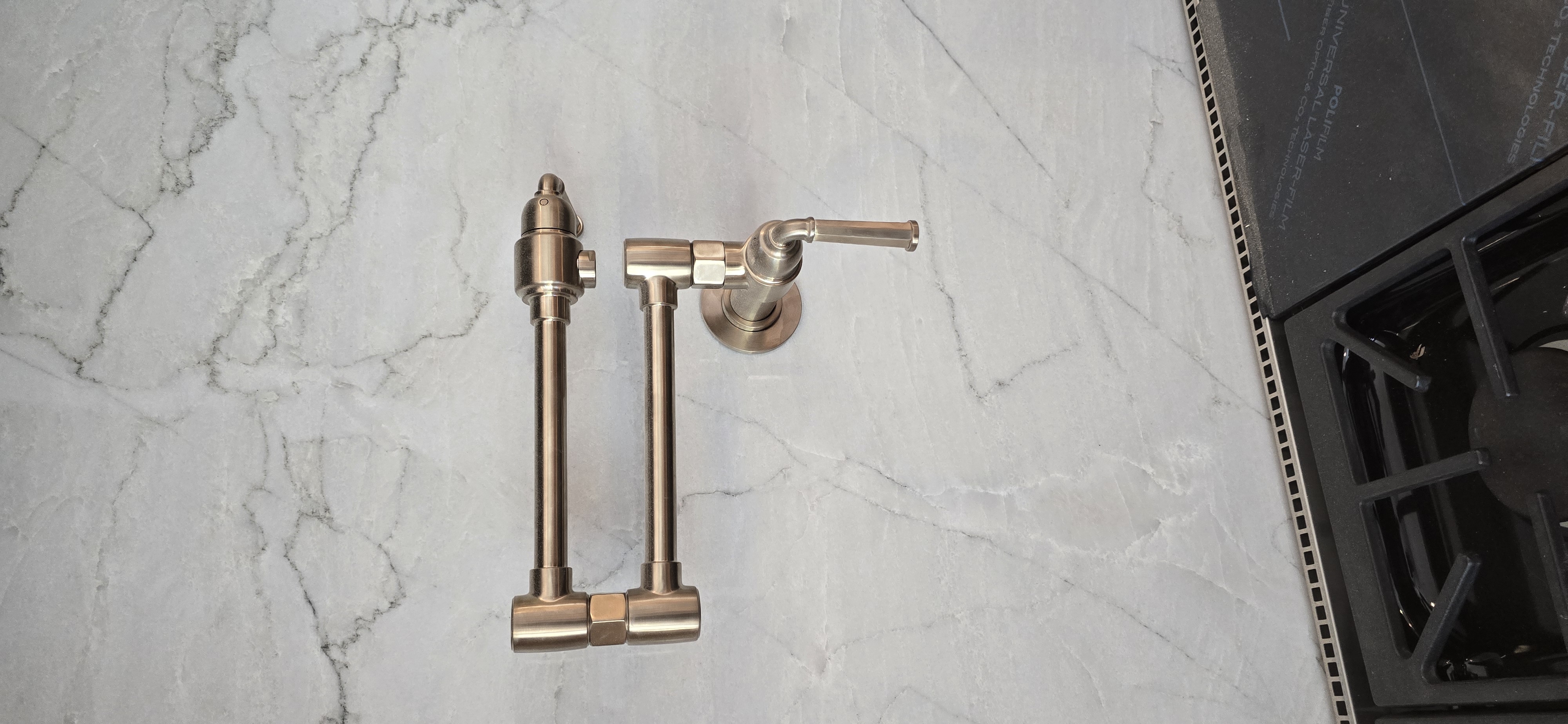 Brushed gold pot filler faucet on marble backsplash
